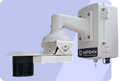 A white, wall-mounted industrial scanner or sensor device with a rectangular arm and black camera, labeled INSPEMON, set against a light purple background.