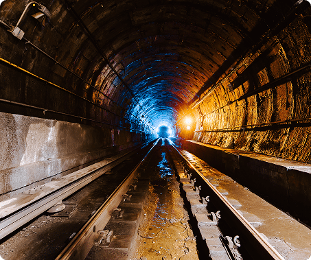 Interior view of a metro tunnel under construction, showing tracks and structural elements.